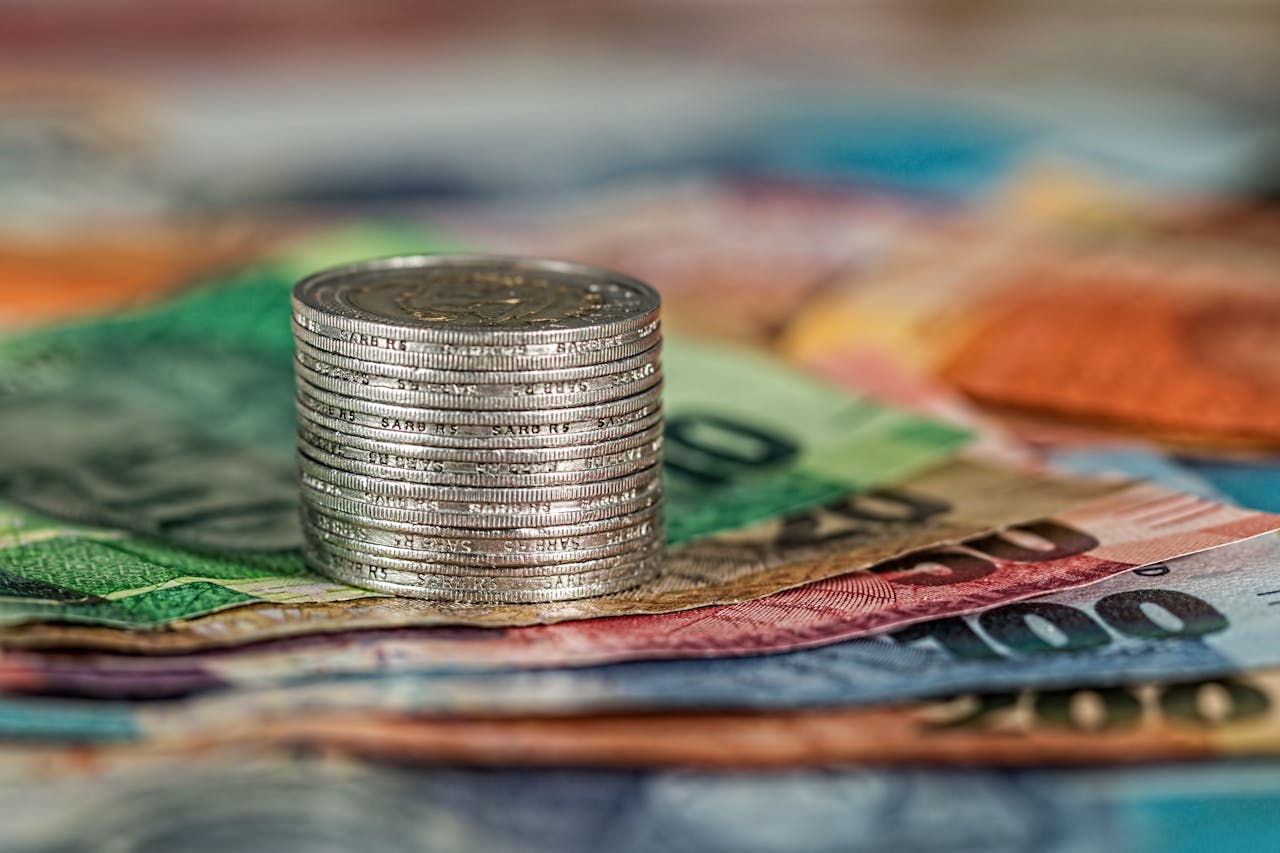 creative A stack of coins on top of various colored banknotes, symbolizing finance and currency.