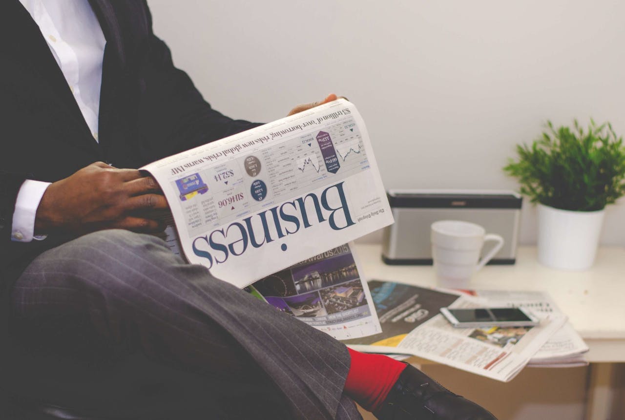Services-02 Businessman reading a financial newspaper at a desk, highlighting finance and commerce theme.